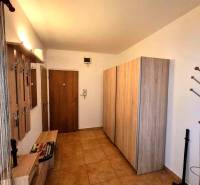 Előszoba egy 2 szobás lakásban fogasokkal, szekrénnyel és fa mintázatú padlóval.