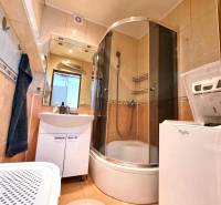 Fürdőszoba egy kétszobás lakásban üveg zuhanykabinnal és mosógéppel.