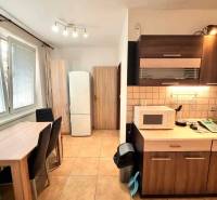 Konyha egy kétszobás lakásban étkezőasztallal és háztartási gépekkel.