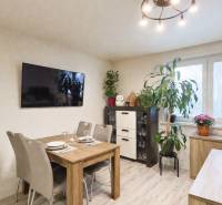 Ebédlő egy családi házban, televízióval, étkezőasztallal és szobanövényekkel.