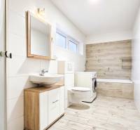 Fürdőszoba egy családi házban fa mintázatú padlóval és mosógéppel.