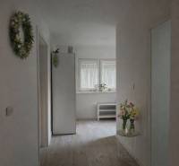 Egy családi ház világos folyosója fa dekoros padlóval, virágokkal és dekorációkkal.