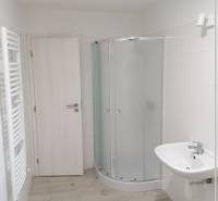 Fürdőszoba családi házban fehér zuhanyzóval és világos, fa mintázatú padlóval.