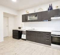 Konyha sötét szekrényekkel, fa dekoros padló, családi ház.