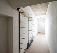 Keskeny belső tér egy raktárban, falon fém akasztókkal.