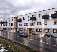 Épület a Šenkvicei Nádražná utcában, raktárak és csarnokok, esti világítással.