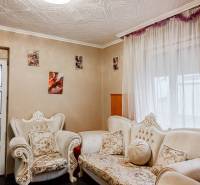 Családi ház nappalija díszes bútorokkal és fényképekkel a falakon.