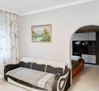 Világos nappali kanapéval, nagy íves átjáróval és virágmintás függönyökkel.