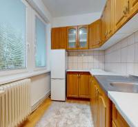 Konyha fa hatású padlóval és fa bútorokkal egy 4 szobás lakásban.