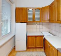 Konyha világos szekrényekkel és fa mintázatú padlóval egy 4 szobás lakásban.