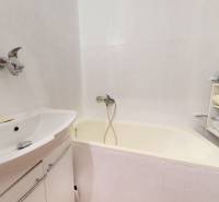 Fürdőszoba káddal és polccal egy 4 szobás lakásban, tárolt ruhákkal.