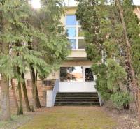 A Hviezdoslav utca fákkal körülvett épületének bejárata Michalovcén, elrejtve a zöldben.