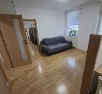 Nappali egy kétszobás lakásban fa dekorációjú padlóval és kanapéval.