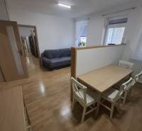 Nappali kanapéval, étkezőasztallal és fa dekorációjú padlóval egy kétszobás lakásban.