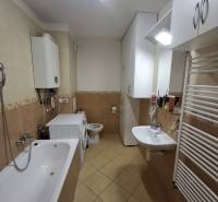 Fürdőszoba egy kétszobás lakásban káddal, mosógéppel és melegvíz-tárolóval.