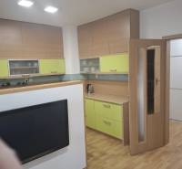 Konyha egy kétszobás lakásban, fa dekor padlóval és színes szekrényekkel.