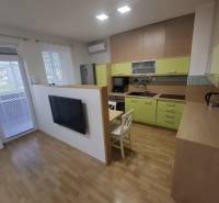 Konyha egy kétszobás lakásban fa dekor padlóval és világos konyhabútorral.