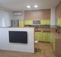 Konyha egy kétszobás lakásban fa dekor padlóval és zöld szekrényekkel.