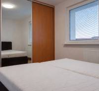 Hálószoba egy háromszobás lakásban nagy ablakkal, beépített szekrénnyel és ággyal.