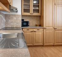 Konyha egy háromszobás lakásban fa dekorációval és modern felszereléssel.