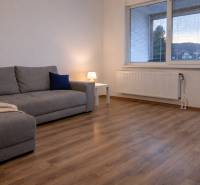 Nappali egy háromszobás lakásban kanapéval és fa dekorációjú padlóval.