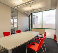 Irodák üvegfallal, fehér asztallal és piros székekkel.