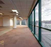 Tágas irodák nagy ablakokkal és széles oszlopokkal, kilátással az utcára.