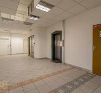 Irodák lifttel és csempével, semleges színek és modern világítás.