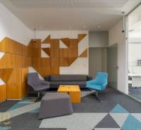 Irodabelső színes ülőhelyekkel, üveggel és geometrikus fa panelekkel.