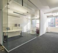 Irodák üveg válaszfalakkal és szőnyegpadlóval, világos terek és természetes fény.