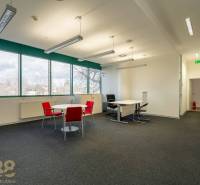 Irodák fekete szőnyeggel, piros székekkel és nagy ablakokkal a földszinten.