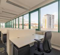 Tágas irodák nyitott boxokkal és nagy ablakokkal, amelyek kilátást nyújtanak a városra.