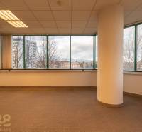 Irodák belső tere nagy ablakokkal és oszloppal, fa dekorációjú padlóval.