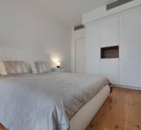 Hálószoba franciaággyal, ruhásszekrénnyel és fa mintázatú padlóval egy kétszobás lakásban.