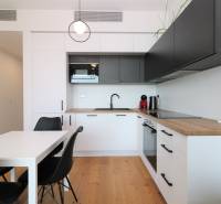 Konyha egy kétszobás lakásban, fa dekoros padlóval és fekete szekrényekkel.