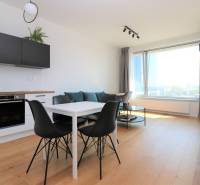 Konyha és étkezőasztal fekete székekkel egy kétszobás lakásban, fa dekorációjú padlóval.