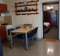 Családi ház étkezőasztallal és székekkel, konyhai rész és nyitott ajtó a hálószobába.