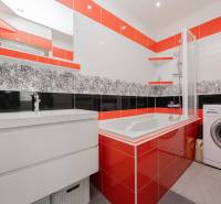 Fürdőszoba zuhanykáddal, mosógéppel és színes csempékkel egy 4 szobás lakásban.