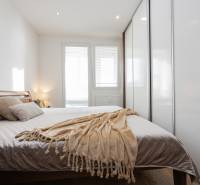 Hálószoba egy 4 szobás lakásban nagy ággyal, takaróval és beépített szekrénnyel.