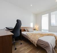 Hálószoba egy 4 szobás lakásban tágas ággyal, asztallal és fa dekorációjú padlóval.