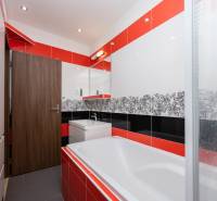 Fürdőszoba egy négyszobás lakásban színes csempékkel és káddal, tükörrel kiegészítve.