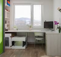 Szoba egy négy szobás lakásban íróasztallal, növényekkel és fa dekorációjú padlóval.