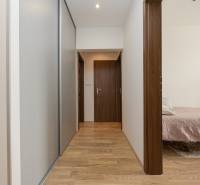 Folyosó szekrénnyel és fa dekorációjú padlóval vezet a helyiségekbe egy 4 szobás lakásban.