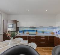 Konyha egy 4 szobás lakásban fehér szekrényekkel és fa mintázatú padlóval.