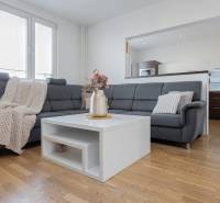 Nappali egy 4 szobás lakásban kanapéval, asztalon lévő virágokkal és fa dekorációjú padlóval.