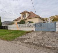 Családi ház Nagydobronyban nagy kerttel, fákkal és beton járdával.