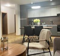 Nappali egy háromszobás lakásban, konyhával, asztallal és fa dekorációjú padlóval.