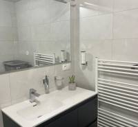 Fürdőszoba egy háromszobás lakásban modern mosdóval, tükörrel és radiátorral.