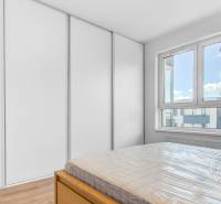 Hálószoba egy kétszobás lakásban fa dekor padlóval, nagy ablakkal és szekrénnyel.