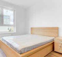 Hálószoba egy kétszobás lakásban fa dekor padlóval és bútorokkal az ablaknál.